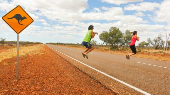 Funny,Couple,Of,Tourists,Pretend,Jumping,Like,Kangaroos,By,Road