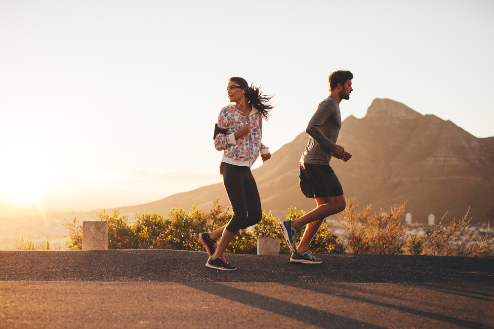 Young,Couple,Jogging,Early,In,Morning,,With,Woman,Looking,Back